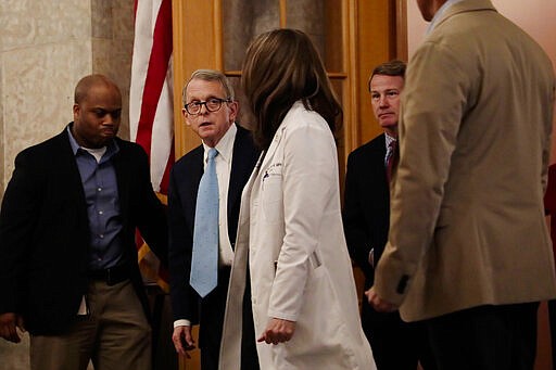 Ohio Gov. Mike DeWine, Ohio Department of Health director Dr. Amy Acton and Ohio Lt. Gov. Jon Husted walk toward the State Room before their update on the state's response to the ongoing COVID-19 coronavirus pandemic on Monday, March 30, 2020 at the Ohio Statehouse in Columbus, Ohio. (Joshua A. Bickel/The Columbus Dispatch via AP)