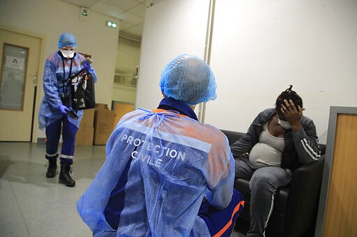 In this photo taken Thursday, March 26, 2020, Vincent Jactel, a member of the Civil Protection service, talks with a 27-year-old pregnant woman suspected of being infected with the Covid-19 virus in a social housing building in Paris. They don't have to put themselves in harm's way, but the volunteers of France's well-known Civil Protection service choose the front line in the fight against the coronavirus. They are often the first to knock on the doors of people calling for help, and who may have the infection or whose confirmed case has taken a downturn. (AP Photo/Michel Euler)