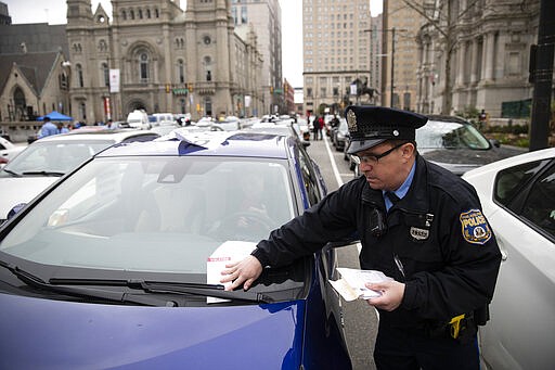 Police ticket protesters' cars blocking traffic as the demonstrators call for officials to release people from jails, prisons, and immigration detention centers in response to the coronavirus outside City Hall in Philadelphia, Monday, March 30, 2020. (AP Photo/Matt Rourke)