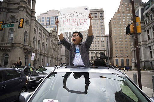 A protester calls for officials to release people from jails, prisons, and immigration detention centers in response to the coronavirus, as he and others block traffic outside City Hall in Philadelphia, Monday, March 30, 2020. (AP Photo/Matt Rourke)