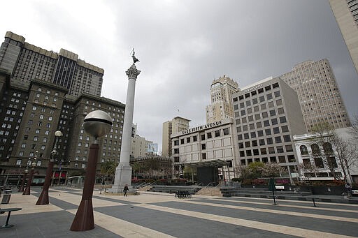 A pedestrian walks through a nearly empty Union Square in San Francisco, Sunday, March 29, 2020. Californians endured a weekend of stepped-up restrictions aimed at keeping them home as much as possible while hospitals and health officials scrambled Sunday to ready themselves for a week that could see the feared dramatic surge in coronavirus cases. (AP Photo/Jeff Chiu)