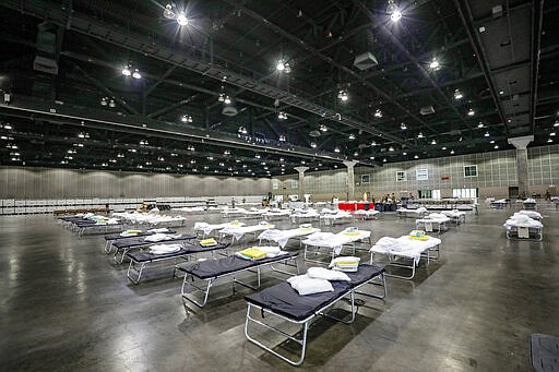 In this Sunday March 29, 2020 photo provided by the office Of Mayor Garretti shows cots set up as a medical station to help relieve nearby hospitals as they fight COVID-19, at the Los Angeles Convention center in downtown Los Angeles. National Guard troops set up beds in the sprawling Los Angeles Convention Center, converting it from a site that normally hosts meetings, trade shows and exhibitions into a field hospital. (Office of Mayor Eric Garcetti via AP)