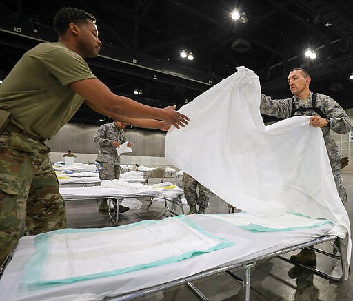 In this Sunday March 29, 2020 provided by the Office Of Mayor Garrcetti National Guard troops set up beds as a medical station to help relieve nearby hospitals as they fight COVID-19 and coronavirus, at the Los Angeles Convention center in downtown Los Angeles. National Guard troops set up beds in the sprawling Los Angeles Convention Center, converting it from a site that normally hosts meetings, trade shows and exhibitions into a field hospital. (Office of Mayor Eric Garcetti via AP)