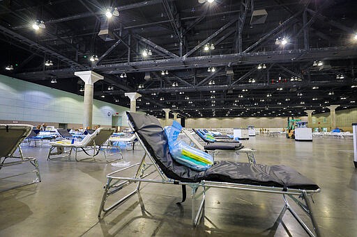 In this Sunday March 29, 2020 provided by the Office Of Mayor Garretti cots are set up as a medical station to help relieve nearby hospitals as they fight COVID-19, at the Los Angeles Convention center in downtown Los Angeles. National Guard troops set up beds in the sprawling Los Angeles Convention Center, converting it from a site that normally hosts meetings, trade shows and exhibitions into a field hospital. (Office of Mayor Eric Garcetti via AP)