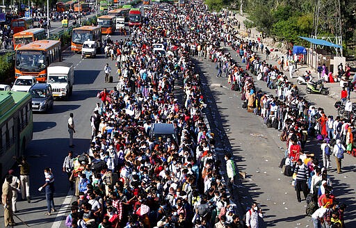 Indian migrant laborers wait for buses provided by the government to transport them to their hometowns, following a lockdown amid concern over spread of coronavirus in New Delhi, India, Saturday, March 28, 2020. Authorities sent a fleet of buses to the outskirts of India's capital on Saturday to meet an exodus of migrant workers desperately trying to reach their home villages during the world's largest coronavirus lockdown. Thousands of people, mostly young male day laborers but also families, fled their New Delhi homes after Prime Minister Narendra Modi announced a 21-day lockdown that began on Wednesday and effectively put millions of Indians who live off daily earnings out of work. (AP Photo)