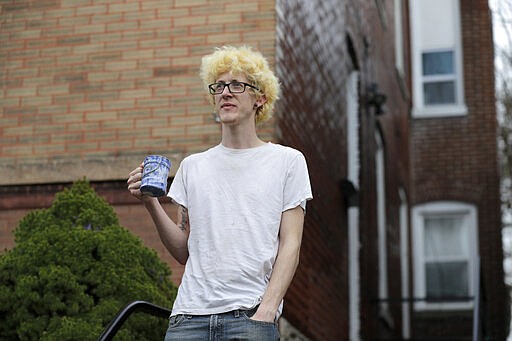 In this Saturday, March 28, 2020 photo, Kyle Kofron poses for a photo outside his home in St. Louis. Kofron still has his job at an ice cream factory, but his three roommates are suddenly unemployed due the the coronavirus pandemic. Kofron is advocating for a rent strike during the outbreak saying it may be their only option. (AP Photo/Jeff Roberson)