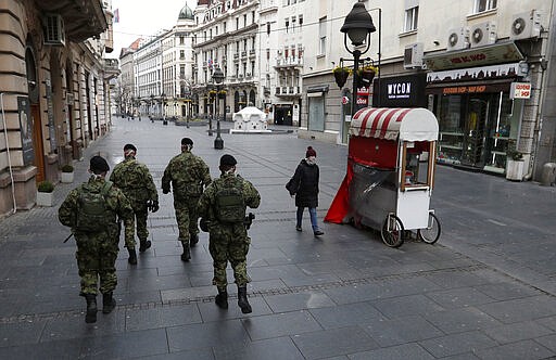 In this March 26, 2020, photo, Serbian army soldiers patrol in Belgrade's main pedestrian street, in Serbia. Since declaring nationwide state of emergency Serbian President Aleksandar Vucic has suspended parliament, giving him widespread powers such as closing borders and introducing a 12-hour curfew. (AP Photo/Darko Vojinovic)