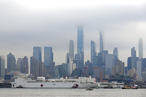 The Navy hospital ship USNS Comfort passes the Manhattan skyline on its way to docking in New York, Monday, March 30, 2020. The ship has 1,000 beds and 12 operating rooms that could be up and running within 24 hours of its arrival on Monday morning. It's expected to bolster a besieged health care system by treating non-coronavirus patients while hospitals treat people with COVID-19. (AP Photo/Seth Wenig)