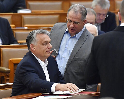 Hungarian Prime Minister Viktor Orban, left, chats with MP of the governing Fidesz party Lajos Kosa during the plenary session of the Parliament in Budapest, Hungary, Monday, March 30, 2020. Later MPs approved legislation that extends a state of emergency and gives the government extraordinary powers to enact measures to contain the spread of the novel coronavirus. (Zoltan Mathe/MTI via AP)