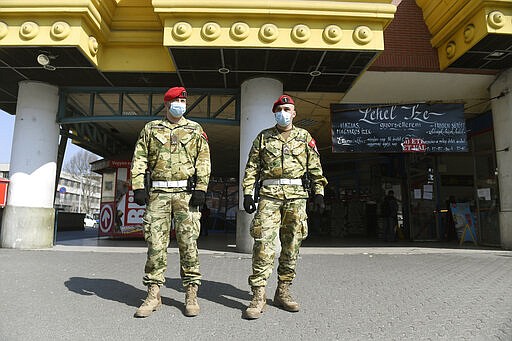 Military policemen patrol the Lehel square market in Budapest, Hungary, Sunday, March 29, 2020. Due to the coronavirus outbreak from 28 March a curfew will be imposed on the entire territory of Hungary until 11 April. For two weeks, homes and residences may only be left for work or for essential needs. Grocery stores, drugstores, pharmacies are only open to those who are over 65-years-old between 9 a.m. and noon. (Szilard Koszticsak/MTI via AP)