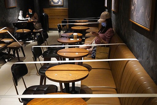 Tables and chairs are taped for the social distancing law enforcement to help curb the spread of the coronavirus at a Starbucks coffee shop in Hong Kong, Monday, March 30, 2020. The new coronavirus causes mild or moderate symptoms for most people, but for some, especially older adults and people with existing health problems, it can cause more severe illness or death. (AP Photo/Vincent Yu)