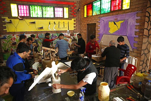 CAPTION ADDITION: ADDS DETAILS ABOUT WHICH PRISON HAD RIOTS: FILE - In this April 3, 2018, file photo, prisoners work in a handicraft workshop at a Kurdish-run prison housing former members of the Islamic State group, in Qamishli, northern Syria. A spokesman for Kurdish-led forces in northeastern Syria said Monday, March. 30, 2020, that they have put an end to riots by Islamic State militants in a prison there. The riots broke out late on Sunday in a prison in the town of Hassakeh and lasted several hours. Kurdish authorities run more than two dozen detention facilities scattered around northeastern Syria, holding about 10,000 IS fighters. (AP Photo/Hussein Malla, File)