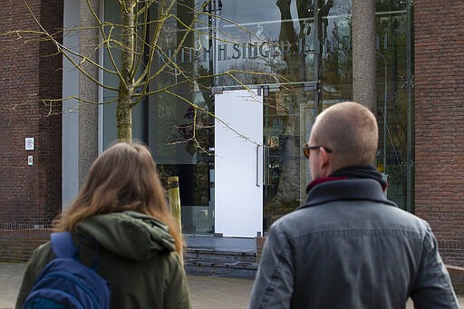 Two people look at the glass door which was smashed during a break-in at the Singer Museum in Laren, Netherlands, Monday March 30, 2020. Police are investigating a break-in at a Dutch art museum that is currently closed because of restrictions aimed at slowing the spread of the coronavirus, the museum and police said Monday. (AP Photo/Peter Dejong)