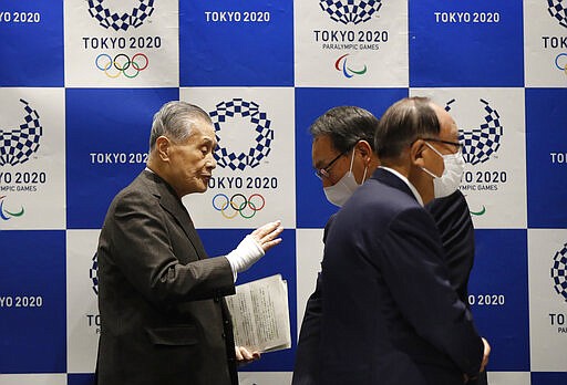 Tokyo Olympic President Yoshiro Mori, left, talks with other board members wearing protective face masks upon arrival at the Tokyo 2020 Executive Board Meeting in Tokyo, Japan Monday, March 30, 2020.  President Mori said Monday he expects to talk with IOC President Thomas Bach this week about rescheduling the games for next year. (Issei Kato/Pool Photo via AP)