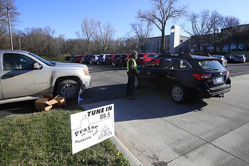 An usher directs attendees to a parking spot for services at Immanuel Lutheran Church In Lawrence, Kan., Sunday, March 29, 2020.  The church plans two &quot;Praise in the Parking Lot&quot; services on Easter due to the coronavirus outbreak. (AP Photo/Orlin Wagner)