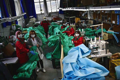 Volunteer workers in a clothing factory manufacturing firefighting gear, pose for a photo as they make hospital gowns for medical staff to protect them from the coronavirus, in Arnedo, northern Spain, Monday, March 30, 2020. The new coronavirus causes mild or moderate symptoms for most people, but for some, especially older adults and people with existing health problems, it can cause more severe illness or death. (AP Photo/Alvaro Barrientos)