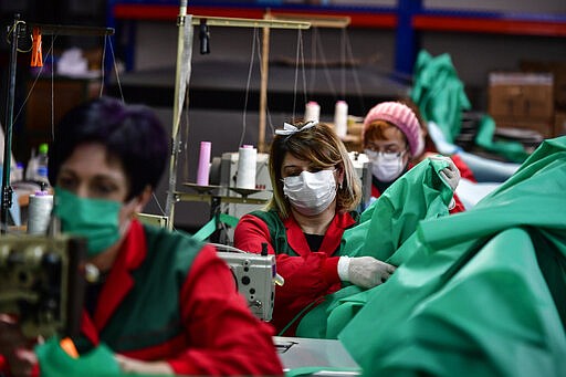 Volunteer workers in a clothing factory manufacturing firefighting gear, make hospital gowns for medical staff to protect them from the coronavirus, in Arnedo, northern Spain, Monday, March 30, 2020. The new coronavirus causes mild or moderate symptoms for most people, but for some, especially older adults and people with existing health problems, it can cause more severe illness or death. (AP Photo/Alvaro Barrientos)