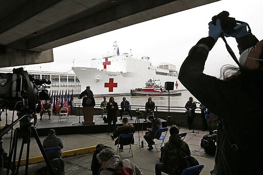 A journalist records speakers at a press briefing following the arrival of the USNS Comfort, a naval hospital ship with a 1,000 bed-capacity, Monday, March 30, 2020, at Pier 90 in New York. The ship will be used to treat patients who do not have the new coronavirus as land-based hospitals fill up to capacity with those that do. (AP Photo/Kathy Willens)