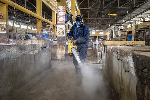 A municipal worker sprays disinfectant in the Grand Market of Dakar, Senegal in an attempt to halt the spread of the new coronavirus Monday, March 30, 2020. The new coronavirus causes mild or moderate symptoms for most people, but for some, especially older adults and people with existing health problems, it can cause more severe illness or death. (AP Photo/Sylvain Cherkaoui)