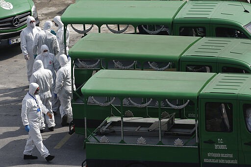 Officials wearing protective face masks and suits as a preventive measure against the spread of the coronavirus wait to load coffins of victims of Covid-19, to hearse trucks outside a morque in Istanbul, Monday, March 30, 2020. The new coronavirus causes mild or moderate symptoms for most people, but for some, especially older adults and people with existing health problems, it can cause more severe illness or death. (AP Photo/Emrah Gurel)