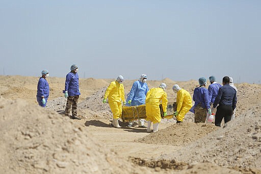 Iraqi health ministry workers carry a coffin of a person who died from coronavirus at a new cemetery for the people who died from Covid-19 outside the town of Najaf, Iraq, Monday, March 30, 2020. (AP Photo/Anmar Khalil)