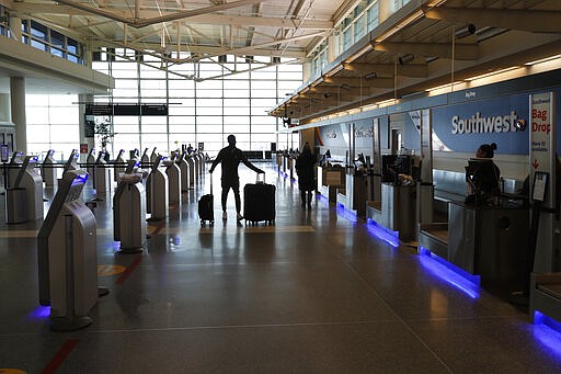 A passenger flying Southwest Airlines wheels his bags to a drop-off kiosk at Midway International Airport Monday, March 30, 2020, in Chicago. The new coronavirus causes mild or moderate symptoms for most people, but for some, especially older adults and people with existing health problems, it can cause more severe illness or death. (AP Photo/Charles Rex Arbogast)