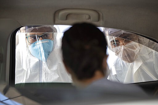 Medical personnel check people inside their cars to find out if they have symptoms of COVID-19 in Guarulhos on the outskirts of Sao Paulo, Brazil, Monday, March 30, 2020. (AP Photo/Andre Penner)