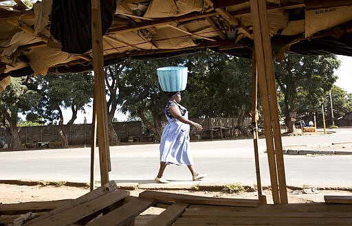 A woman carries an empty basket in a deserted market in Harare, Zimbabwe, Monday, March, 30, 2020. Zimbabwe went into a lockdown for 21 days in an effort to curb the spread of the coronoavirus. The new coronavirus causes mild or moderate symptoms for most people, but for some, especially older adults and people with existing health problems,it can cause more severe illness or death. (AP Photo/Tsvangirayi Mukwazhi)