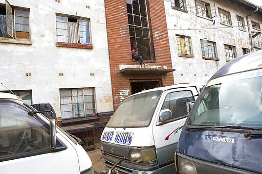 A man sits on a balcony at a block of flats in Harare, Zimbabwe, Monday, March, 30, 2020. Zimbabwe went into a lockdown for 21 days in an effort to curb the spread of the coronoavirus. The new coronavirus causes mild or moderate symptoms for most people, but for some, especially older adults and people with existing health problems,it can cause more severe illness or death. (AP Photo/Tsvangirayi Mukwazhi)