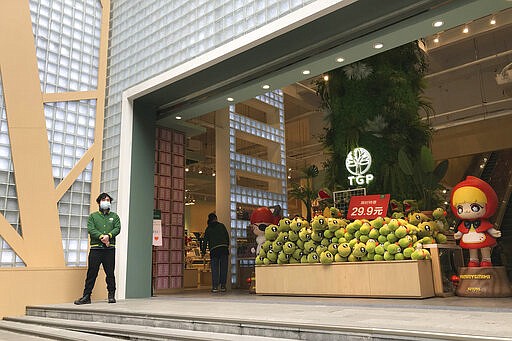 A store employee waits outside for customers at a re-opened retail street in Wuhan in central China's Hubei province on Monday, March 30, 2020. Shopkeepers in the city at the center of China's virus outbreak were reopening Monday but customers were scarce after authorities lifted more of the anti-virus controls that kept tens of millions of people at home for two months. (AP Photo/Olivia Zhang)