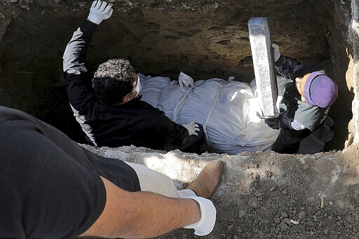 People wearing masks and gloves bury a victim who died after being infected with the new coronavirus, at a cemetery just outside Tehran, Iran, Monday, March 30, 2020.The new coronavirus causes mild or moderate symptoms for most people, but for some, especially older adults and people with existing health problems, it can cause more severe illness or death. (AP Photo/Ebrahim Noroozi)