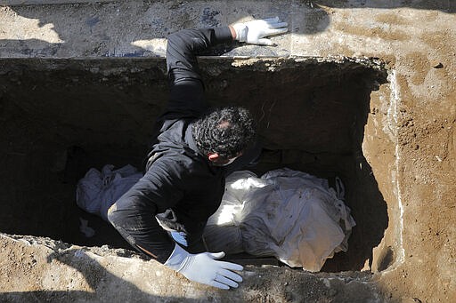 A man wearing a mask and gloves attends a funeral of a victim who died after being infected with the new coronavirus, at a cemetery just outside Tehran, Iran, Monday, March 30, 2020. The new coronavirus causes mild or moderate symptoms for most people, but for some, especially older adults and people with existing health problems, it can cause more severe illness or death. (AP Photo/Ebrahim Noroozi)