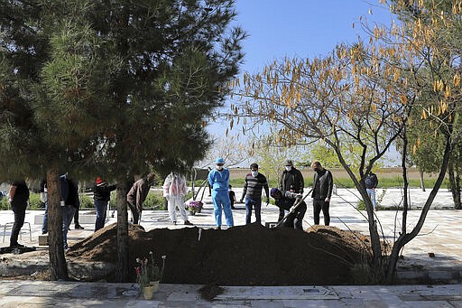 People wearing protective clothings, masks and gloves attend a funeral of a victim who died after being infected with the new coronavirus, at a cemetery just outside Tehran, Iran, Monday, March 30, 2020. The new coronavirus causes mild or moderate symptoms for most people, but for some, especially older adults and people with existing health problems, it can cause more severe illness or death. (AP Photo/Ebrahim Noroozi)