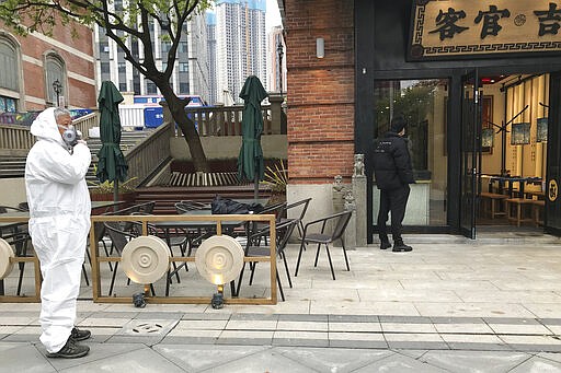 A store worker in protective suit waits for customers at a re-opened retail street in Wuhan in central China's Hubei province on Monday, March 30, 2020. Shopkeepers in the city at the center of China's virus outbreak were reopening Monday but customers were scarce after authorities lifted more of the anti-virus controls that kept tens of millions of people at home for two months. (AP Photo/Olivia Zhang)