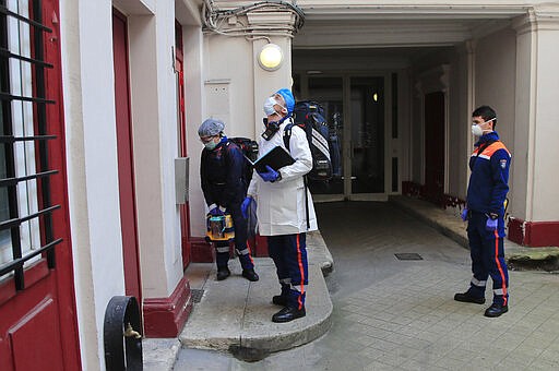 In this photo taken Saturday March 28, 2020, members of the Civil Protection service, Noemie Biamba, left, Cyril Lamriben, center, and Pierre Leroux wait before checking a woman possibly infected with the Covid-19 virus in Paris. They don't have to put themselves in harm's way, but the volunteers of France's well-known Civil Protection service choose the front line in the fight against the coronavirus. The service is a mainstay among France's first responder sector with 32,000 volunteers based in 400 locations around the country. (AP Photo/Michel Euler)