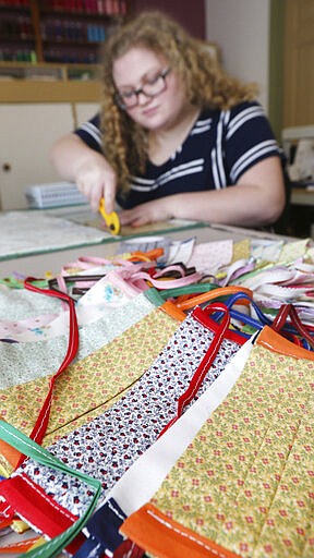 Intern Megan Murphy cuts fabric to make health masks at the Eau Claire Children's Theatre in Eau Claire, Wis., on March 24, 2020. Creating a mask involves several steps and takes ECCT employees around 20 minutes to finish. (Dan Reiland/The Eau Claire Leader-Telegram via AP)