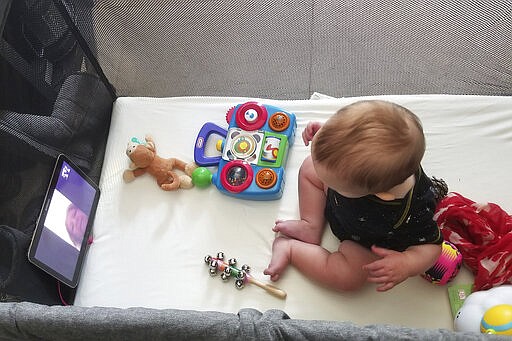 In this March 19, 2020, photo provided by Julie Bufkin, her 7-month-old boy, Calvin, interacts with his grandmother, Debbie Cameron, in Chandler, Ariz., on a FaceTime call from his crib in Tempe, Ariz. The Camerons are among the grandparents all over the country going through a piercing distance from their loved ones for their own protection during the coronavirus crisis. (Julie Bufkin via AP)