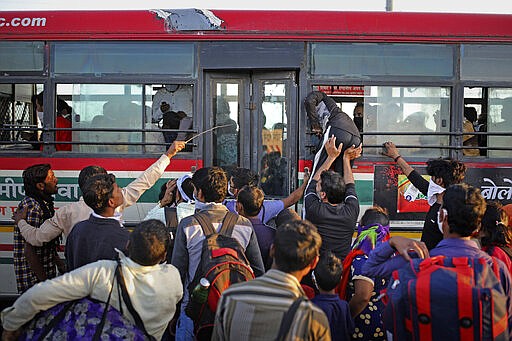 In this Saturday, March 28, 2020, photo, an Indian migrant worker tries to make his way through a window of a bus provided by the government, as they leave for their respective villages following a lockdown amid concern over spread of coronavirus in New Delhi, India. Over the past week, India&#146;s migrant workers - the mainstay of the country&#146;s labor force - spilled out of big cities that have been shuttered due to the coronavirus and returned to their villages, sparking fears that the virus could spread to the countryside. It was an exodus unlike anything seen in India since the 1947 Partition, when British colothe subcontinent, with the 21-day lockdown leaving millions of migrants with no choice but to return to their home villages. (AP Photo/Altaf Qadri)