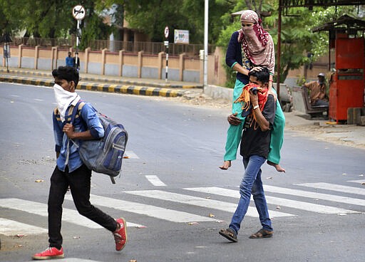 In this Thursday, March 26, 2020, file photo, a migrant worker Ramesh Meena from neighboring state of Rajasthan carries her wife Ramila Meena, who fractured her leg, on his shoulder, as they leave for their village after the city comes under lock down as a precautionary measure against COVID-19 in Ahmedabad, India. Over the past week, India&#146;s migrant workers - the mainstay of the country&#146;s labor force - spilled out of big cities that have been shuttered due to the coronavirus and returned to their villages, sparking fears that the virus could spread to the countryside. It was an exodus unlike anything seen in India since the 1947 Partition, when British colothe subcontinent, with the 21-day lockdown leaving millions of migrants with no choice but to return to their home villages. (AP Photo/Ajit Solanki, File)