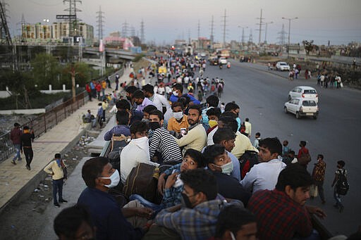 In this Saturday, March 28, 2020, photo, Indian migrant workers sit atop a bus, provided by the government, as others walk along an expressway to their villages following a lockdown amid concern over spread of coronavirus in New Delhi, India. Over the past week, India&#146;s migrant workers - the mainstay of the country&#146;s labor force - spilled out of big cities that have been shuttered due to the coronavirus and returned to their villages, sparking fears that the virus could spread to the countryside. It was an exodus unlike anything seen in India since the 1947 Partition, when British colothe subcontinent, with the 21-day lockdown leaving millions of migrants with no choice but to return to their home villages. (AP Photo/Altaf Qadri)