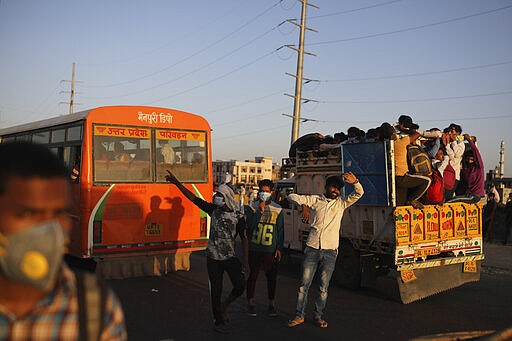 In this Saturday, March 28, 2020, file photo, Indian men try to stop vehicles for migrant workers waiting for transportation to their respective villages following a lockdown amid concern over spread of coronavirus in New Delhi, India. Over the past week, India&#146;s migrant workers - the mainstay of the country&#146;s labor force - spilled out of big cities that have been shuttered due to the coronavirus and returned to their villages, sparking fears that the virus could spread to the countryside. It was an exodus unlike anything seen in India since the 1947 Partition, when British colothe subcontinent, with the 21-day lockdown leaving millions of migrants with no choice but to return to their home villages. (AP Photo/Altaf Qadri, File)