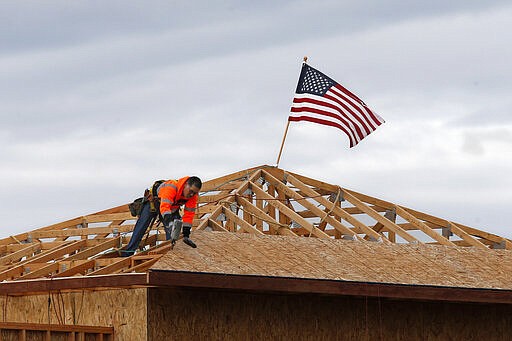 The American flag flutters in the wind as work is done on the roof of a building under construction in Sacramento, Calif., Tuesday, March 31, 2020. While most Californian's have spent more than a week under a mandatory stay-at-home order, because of the coronavirus, construction work is among the jobs exempt as part of the &quot;essential infrastructure.&quot; (AP Photo/Rich Pedroncelli)