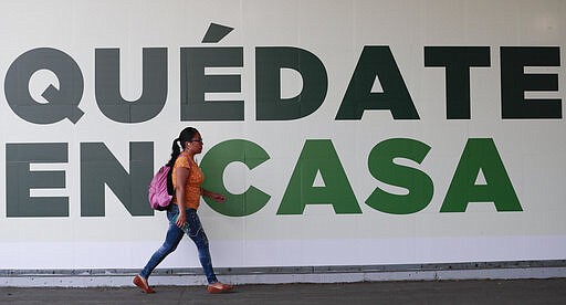 A woman walks past a sign that reads in Spanish &quot;Stay home&quot; in Mexico City, Tuesday, March 31, 2020. Mexico's government has broadened its shutdown of &quot;non essential activities,&quot; and prohibited gatherings of more than 50 people as a way to help slow down the spread of the new coronavirus. The one-month emergency measures will be in effect from March 30 to April 30. (AP Photo/Eduardo Verdugo)