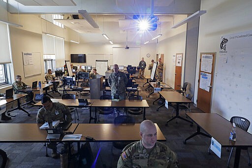 Washington Army National Guard Col. Kevin McMahan, center, stands in the middle of the operations room for the coordination of Washington National Guard troops and active duty U.S. Army soldiers working in Washington state in response to the new coronavirus outbreak, Tuesday, March 31, 2020, at Camp Murray, Wash. McMahan is the title 32 deputy commander with Joint Taskforce Steelhead, the coordinated effort between the Washington National Guard and a field hospital unit of U.S. Army soldiers from Colorado who are setting up a field hospital for non-coronavirus patients at the CenturyLink Field Events Center in Seattle. (AP Photo/Ted S. Warren)