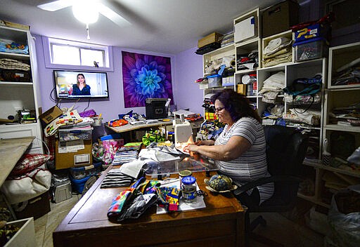 Donna Tosi, of Vernon, Vt., works on making masks for the Brattleboro Retreat in her basement sewing room on March 31, 2020 while watching the news about the COVID-19 outbreak. Tosi has made roughly 135 masks so far. (Kristopher Radder/The Brattleboro Reformer via AP)