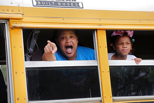 A congregant in a church bus yells out to news media as they leave services at the Life Tabernacle Church in Central, La., Sunday, March 29, 2020. Pastor Tony Spell has defied a shelter-in-place order by Louisiana Gov. John Bel Edwards, due to the new coronavirus pandemic, and continues to hold church services with hundreds of congregants. (AP Photo/Gerald Herbert)