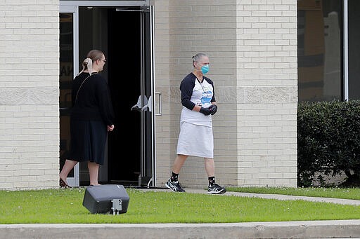 A person wears a mask as she walks outside the Life Tabernacle Church after services in Central, La., Sunday, March 29, 2020. Pastor Tony Spell has defied a shelter-in-place order by Louisiana Gov. John Bel Edwards, due to the new coronavirus pandemic, and continues to hold church services with hundreds of congregants. (AP Photo/Gerald Herbert)