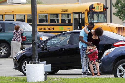 Congregants at the Life Tabernacle Church embrace after services in Central, La., Sunday, March 29, 2020. Pastor Tony Spell has defied a shelter-in-place order by Louisiana Gov. John Bel Edwards, due to the new coronavirus pandemic, and continues to hold church services with hundreds of congregants. (AP Photo/Gerald Herbert)