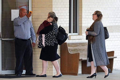 A man takes temperature scans as congregants arrive for evening service at the Life Tabernacle Church in Central, La., Tuesday, March 31, 2020. Pastor Tony Spell says he will keep violating a ban on gatherings put in place to control the spread of the coronavirus because God told him to. (AP Photo/Gerald Herbert)