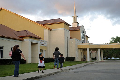 Congregants arrive for evening service at the Life Tabernacle Church in Central, La., Tuesday, March 31, 2020. Pastor Tony Spell held services despite being charged with misdemeanors today, for holding services against Gov. John Bel Edwards shelter-in-place order due to the new coronavirus pandemic. (AP Photo/Gerald Herbert)